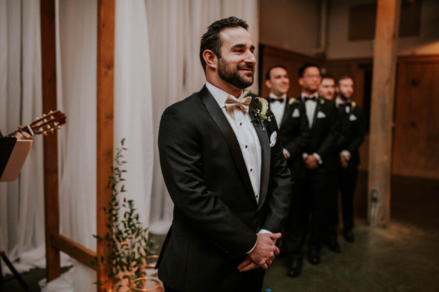 Groom smiling as bride walks down the aisle