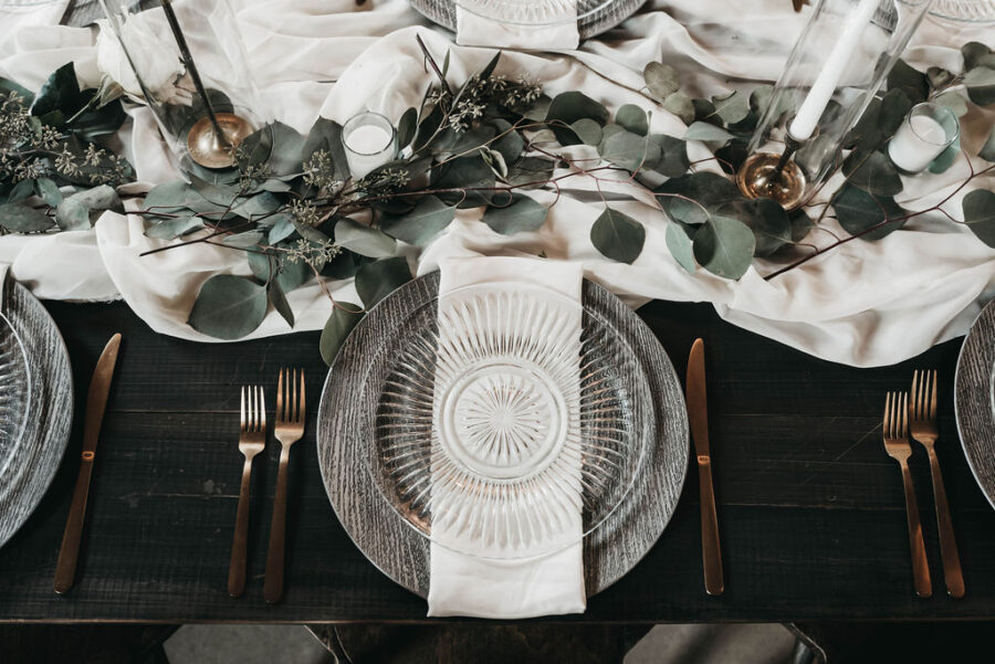 wedding place setting with clear plates and white linens