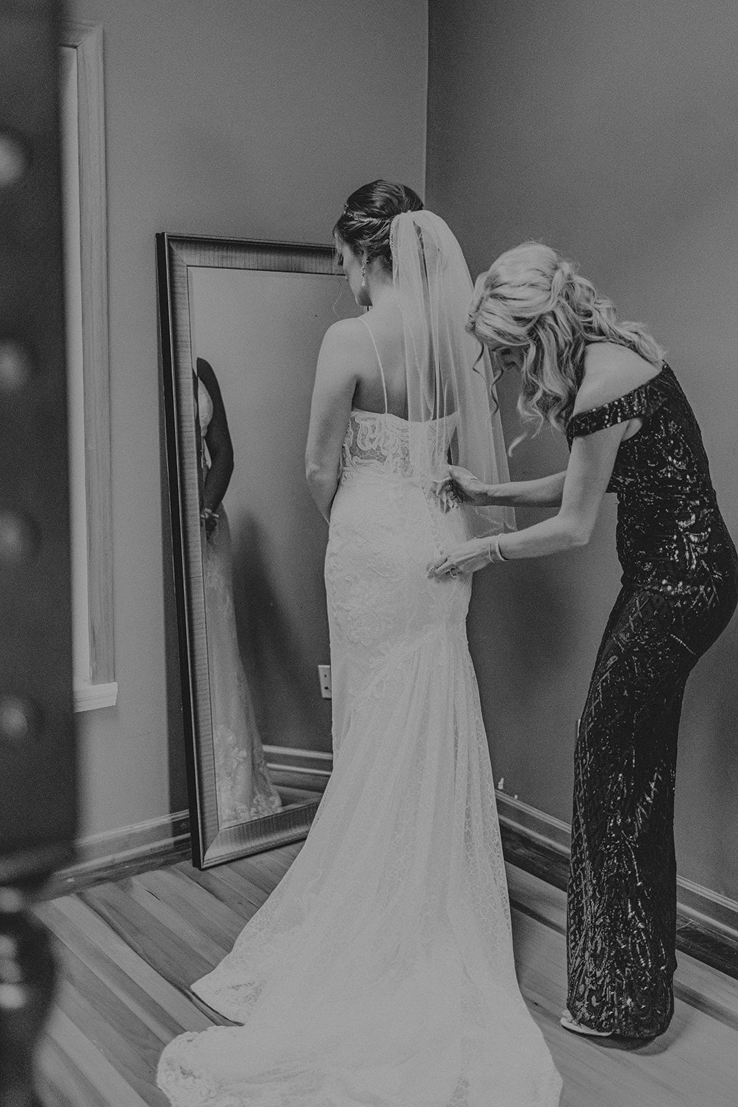 Mother of the Bride helping Bride into wedding dress