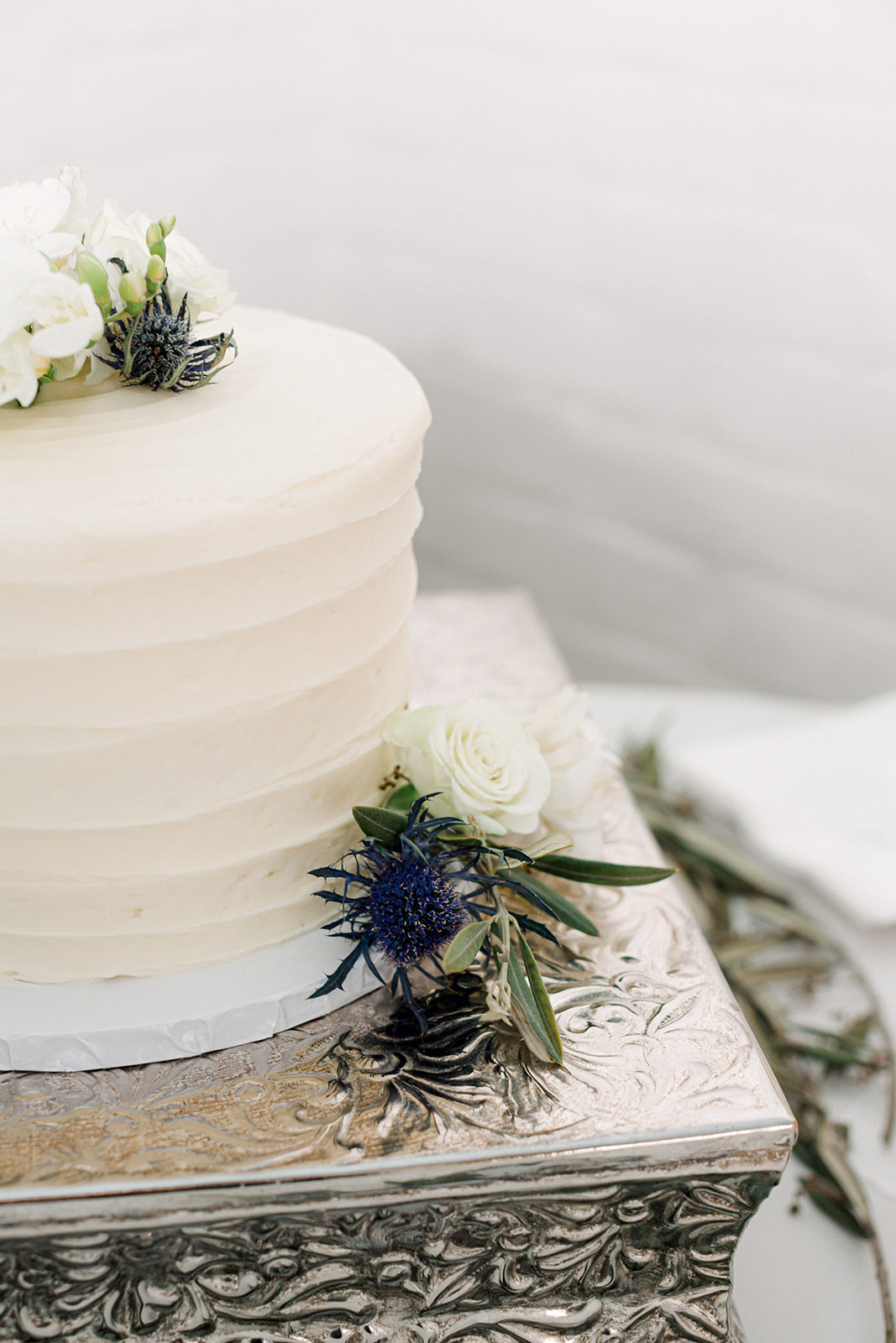 Simple white wedding cake with blue thistle flowers
