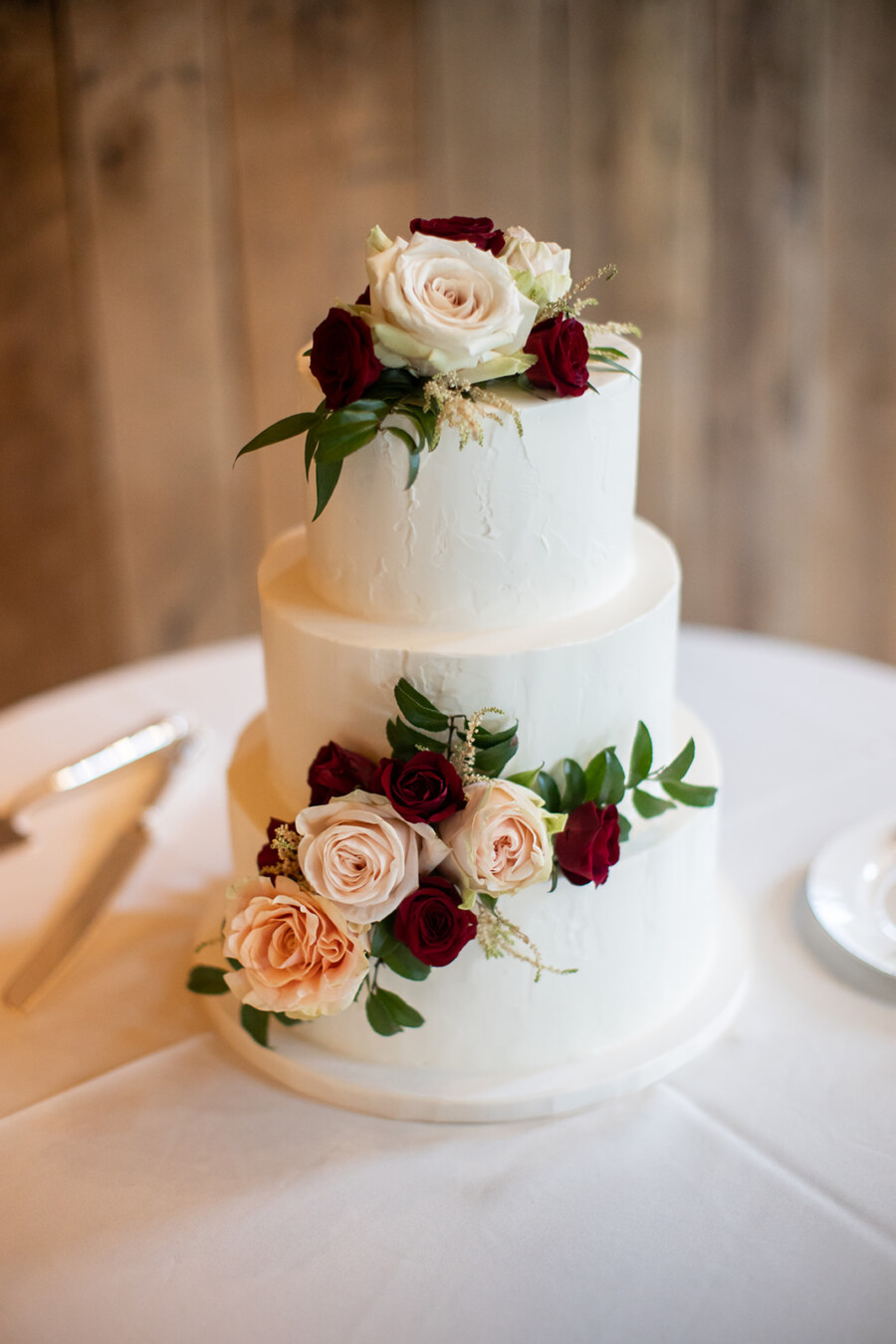 White wedding cake with red and pink flowers
